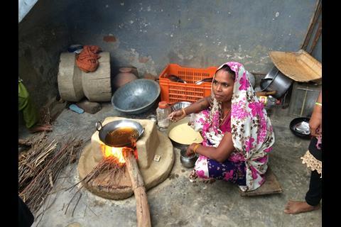 An image of a woman cooking with biomass on an earth stove